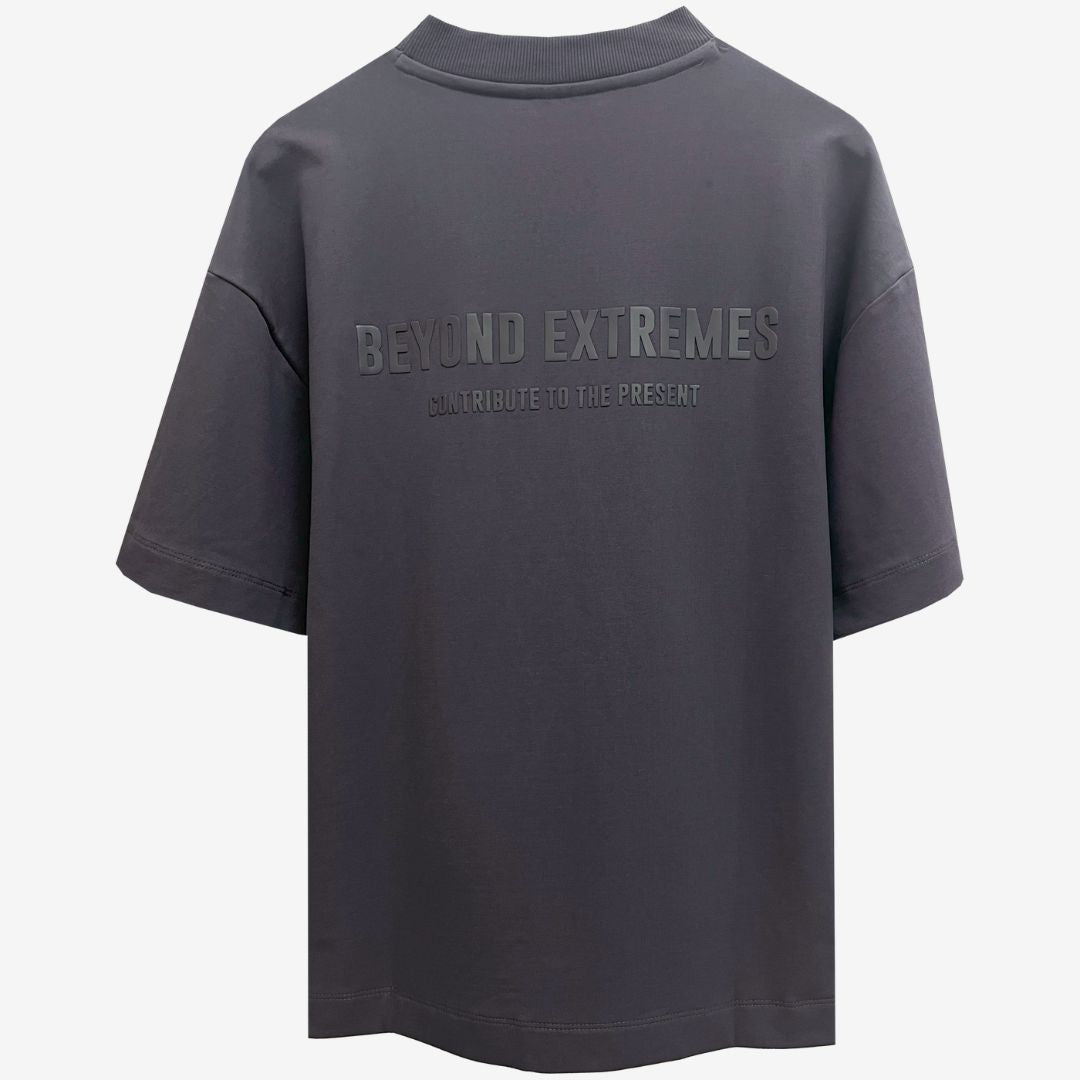 A grey oversized t-shirt featuring the words "Beyond Extremes," showcasing luxury Indian streetwear style.